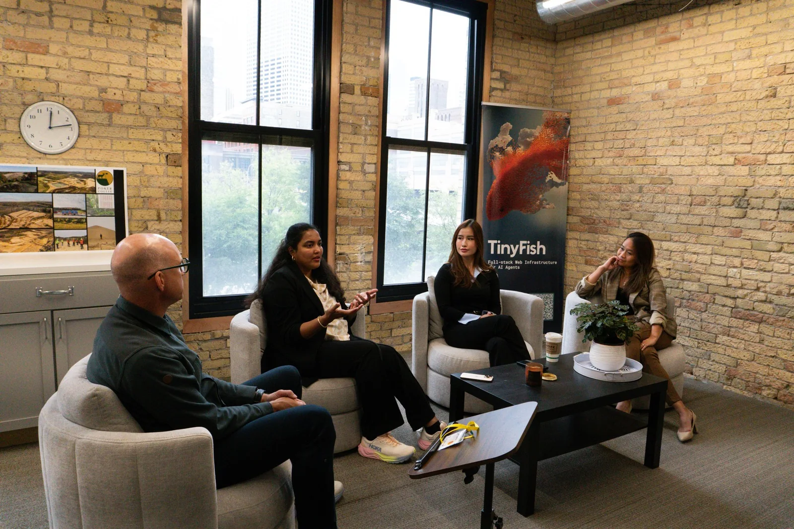 Speakers in conversation in the brick-walled meeting room at Origin House on TCSW opening day
