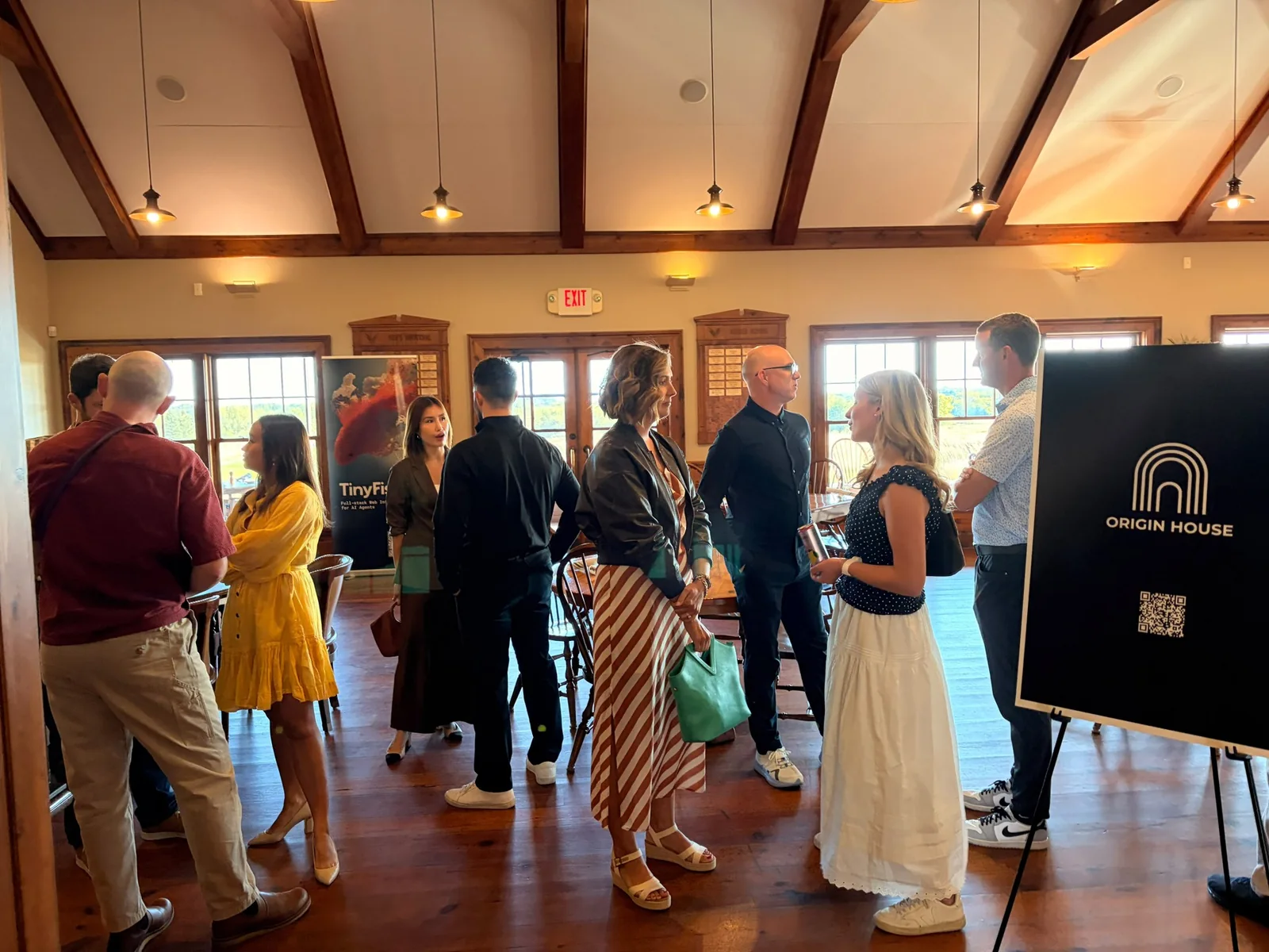 Guests talking in the dinner room at Windsong Farm beside Origin House and TinyFish banners
