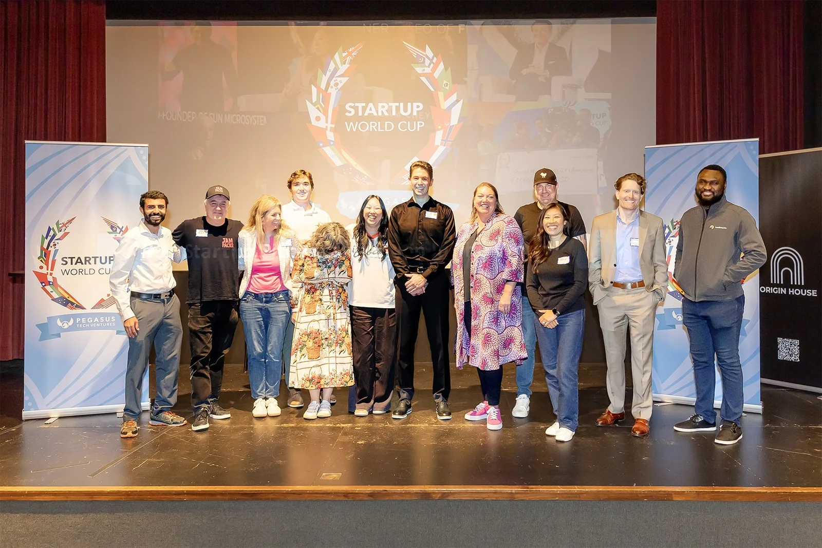 Startup World Cup Twin Cities finalists together on stage with Origin House and Startup World Cup banners